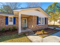 Brick ranch home with blue shutters, updated front door, and landscaping at 7643 Linsley Dr, North Charleston, SC 29418