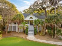 Stunning white home with gray accents,palm trees, and a welcoming staircase at 6800 Back Bay Dr, Isle of Palms, SC 29451