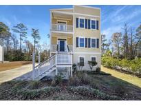 Two-story house with light beige siding, dark shutters, and a white porch at 7228 Mossy Creek Ln, Hanahan, SC 29410
