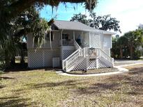 Charming raised cottage with white exterior, lattice details, and spacious yard at 745 Fairway Dr, Edisto Island, SC 29438