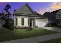 Tan house with white garage door, landscaping, and a tree in the front yard at 9797 Black Willow Ln, Ladson, SC 29456