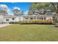 Charming white house with a spacious lawn, covered porch, and mature trees at 5093 Chateau Ave, North Charleston, SC 29405