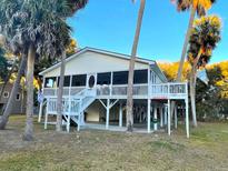 Elevated beach home with large deck, screened porch, and tropical landscaping at 603 Portia St, Edisto Beach, SC 29438
