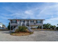 Elevated beach house with white stairs and American flag at 1308 Palmetto Blvd Blvd, Edisto Beach, SC 29438