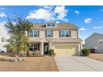 Two-story house with beige siding, yellow garage door, and landscaping at 148 Carolina Wren Ave, Moncks Corner, SC 29461