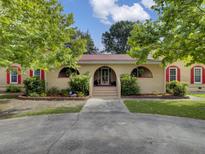 Tan house with red roof, arched entryway, and landscaped yard at 506 Gross Ave, Moncks Corner, SC 29461