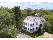 White two-story house with wrap-around porch, surrounded by lush greenery at 124 Mary St, Mount Pleasant, SC 29464