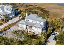 Aerial view of a white two-story house with a metal roof, situated near water at 2618 Raven Dr, Sullivans Island, SC 29482