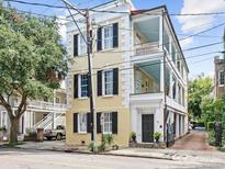 Three-story yellow house with black shutters, white columns, and a gated courtyard at 53 Hasell Street St # H, Charleston, SC 29401