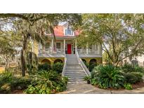 Two-story home with red metal roof, white columns, and lush landscaping at 1871 Headquarters Plantation Dr, Johns Island, SC 29455