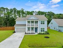 Two-story light blue house with gray roof, two-car garage, and landscaped yard at 4041 Oxeye Loop, Johns Island, SC 29455