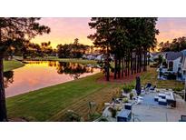 Peaceful backyard oasis with patio furniture, fire pit and pond view at sunset at 511 Tidewater Chase Ln, Summerville, SC 29486