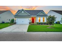 Curb appeal abounds in this charming one-story home featuring a red door and well-manicured lawn at 554 Tidewater Chase Ln, Summerville, SC 29486