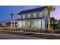 Charming two-story light blue house with a front porch and palm trees at 711 Blueway Ave, Summerville, SC 29486