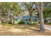 Charming yellow cottage with teal accents, surrounded by lush landscaping at 10 Chapman Ave, Isle of Palms, SC 29451