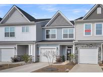 Two-story townhouses with gray and blue siding, white garage doors, and landscaping at 396 Painted Lady Ln, Goose Creek, SC 29445