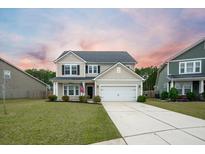 Two-story house with beige siding, a white garage door, and a well-manicured lawn at 401 Huckleberry Ct, Summerville, SC 29486