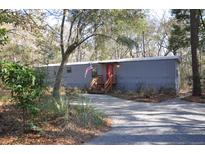 Gray mobile home with red door, nestled in wooded lot at 6321 Bears Bluff Rd, Wadmalaw Island, SC 29487