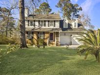 Two-story brick house with a large front yard, two-car garage, and mature trees at 1001 Shinnecock Hills Ct, Summerville, SC 29483