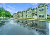 Row of green townhomes with white trim and wet parking lot at 1304 Twin Rivers Dr # 56, Wando, SC 29492