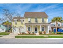 Two-story yellow house with white columns, shutters, and a two-car garage at 2725 Battery Pringle Dr, Johns Island, SC 29455