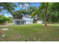 Expansive backyard featuring a well-maintained lawn, mature trees, and a charming home with a covered porch at 1787 Hay Rd, Johns Island, SC 29455