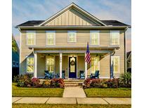 Charming two-story home with a welcoming front porch, beautiful landscaping, and an American flag at 306 Ripple Park Dr, Summerville, SC 29486