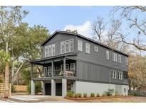 Striking two-story home with gray siding, modern windows, and a covered porch, surrounded by lush trees at 915 Dill Ave, Charleston, SC 29412