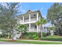 Charming two-story home featuring double porches, a landscaped yard with palm trees, and a classic coastal design at 164 River Green Pl, Charleston, SC 29492