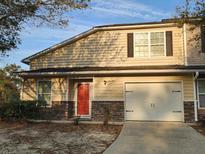 Charming townhome featuring a red front door, one-car garage, and stone accents at 204 Tyner Trl, Summerville, SC 29486