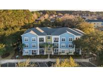 View of colorful apartment building with balconies, palm trees, and parking at 2200 Belle Isle Ave # 103, Mount Pleasant, SC 29464
