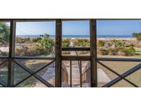Scenic view from a screened porch overlooking a sandy path to the beach and ocean at 3408 Palmetto Blvd, Edisto Island, SC 29438