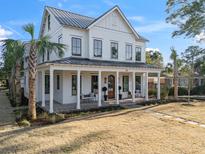 Stunning two-story white farmhouse featuring a welcoming front porch and meticulous landscaping at 1119 Simmons St, Mount Pleasant, SC 29464