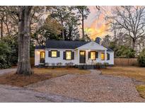 Charming home with white siding, black shutters, and a cozy front porch at sunset at 1204 Vienna Woods Rd, Hanahan, SC 29410