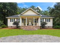 Charming single-story home featuring a cozy front porch with rocking chairs and well-manicured landscaping at 140 Old Plantation Ln, Moncks Corner, SC 29461