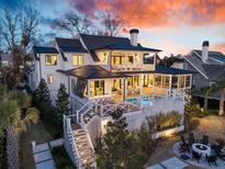 Expansive modern farmhouse with a pool, outdoor living, and a fire pit at sunset at 151 Brailsford St, Charleston, SC 29492