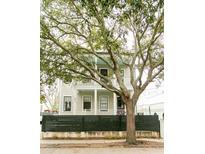 Charming two-story home with a light neutral exterior, featuring a double porch, a green fence, and a beautiful mature tree at 22 1/2 Mary St # A B C, Charleston, SC 29403