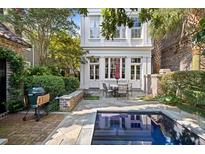 Charming backyard featuring a grill, patio dining set, and a refreshing in-ground swimming pool at 23 Elliott St, Charleston, SC 29401