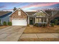 Charming home featuring stone accents, two-car garage, inviting front porch, and well-maintained landscaping at 3034 Cross Vine Ln, Summerville, SC 29483