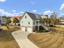 Charming coastal home featuring a two-car garage, a welcoming front porch, and landscaped surroundings at 4258 Jacobs Pt Ct, Ravenel, SC 29470