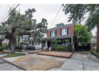 Charming two-story brick home featuring traditional architecture and a well-manicured front yard and mature shade trees at 52 Parkwood Ave, Charleston, SC 29403