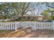 Charming brick home with a white picket fence and mature shade trees in a well-maintained front yard at 1317 Orange Grove Rd, Charleston, SC 29407