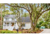 Charming two-story home with a light gray exterior, blue shutters, and mature trees at 23 Edgewater Aly, Isle of Palms, SC 29451
