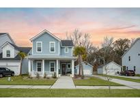 Charming two-story home with a welcoming front porch, manicured lawn, and detached garage at 2710 Mcfadden Way, Johns Island, SC 29455