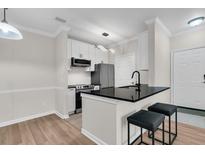 Modern kitchen features white cabinetry, stainless steel appliances, and a sleek black countertop with seating at 45 Sycamore Ave # 1821, Charleston, SC 29407
