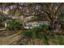 Charming single-story home featuring a white brick facade, mature trees, and lush landscaping at 924 S Shem Dr, Mount Pleasant, SC 29464