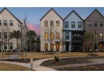 Charming multi-story townhomes with manicured lawns, sidewalks, and lush trees at twilight at 1566 Hancock St # B-1, Mount Pleasant, SC 29464