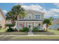 Charming two-story home with a welcoming porch, American flag, and lush tropical landscaping at 213 Crossandra Ave, Summerville, SC 29483