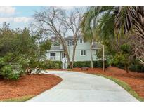 Charming two-story home with lush landscaping, curved driveway, and welcoming front porch at 3619 Loggerhead Ct, Seabrook Island, SC 29455