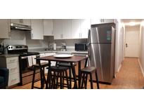 Open kitchen with stainless steel appliances, white cabinets, and a modern kitchen island with stools at 40 Bee St # 112, Charleston, SC 29403